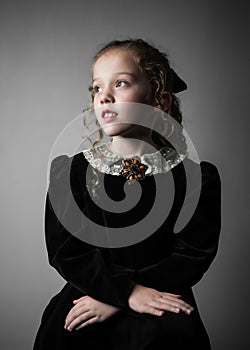 Beautiful young girl in black 1890s English Victorian 18th century child period dress elegant white lace collar antique broach