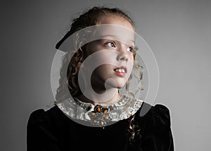 Beautiful young girl in black 1890s English Victorian 18th century child period dress elegant white lace collar antique broach