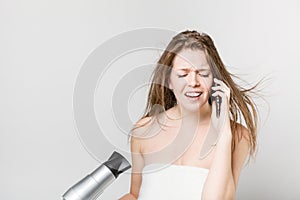 Beautiful young girl blow drying her hair while talking on the m