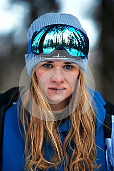 Beautiful young girl in a blue ski suit and helmet. On the head are glasses for snowboarding. Snow-covered mountain