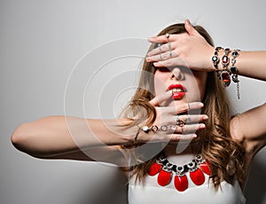 Beautiful young girl with bright lips in the studio. Jewelry costume jewelry - earrings, bracelet, red necklace.