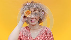Beautiful young girl covering her eye with an orange gerbera daisy flower
