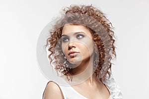 A beautiful young girl with curly hair on gray background