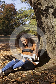 Beautiful young girl with dark curly hair using tablet computer, outdoor.