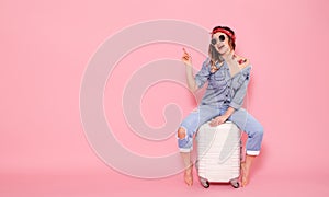 Beautiful young girl in denim shirt with water decal tattoo flowers sticker smiling and sitting on suitcase