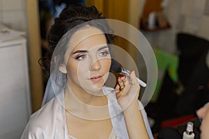 Beautiful young girl do makeup at home.