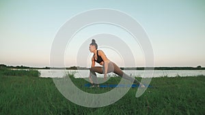 Beautiful young girl doing yoga at sunrise at lake. Healthy lifestyle concept
