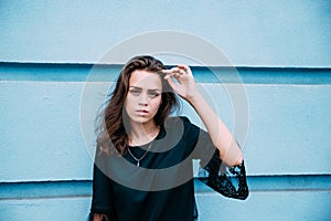 Beautiful young girl in a dress near a blue stone wall