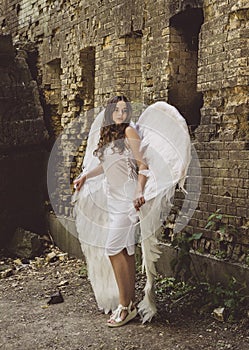 Beautiful young girl in a dress with white angel wings.