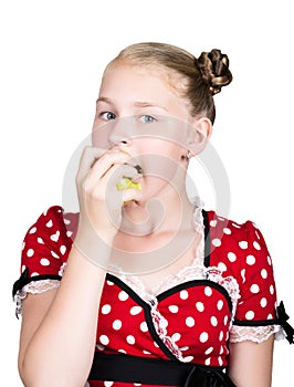 Beautiful young girl dressed in a red dress with white polka dots eating an apple. healthy food - strong teeth concept