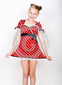 Beautiful young girl dressed in a red dress with white polka dots. Funny kids pamper and posing