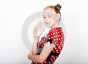 Beautiful young girl dressed in a red dress with white polka dots. Funny kids pamper and posing