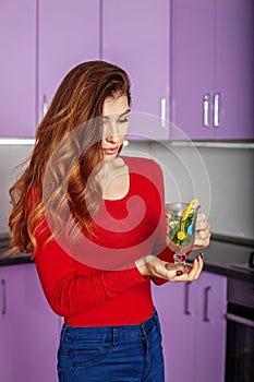 Beautiful young girl drinks hot tea with mint in a glass cup. Th