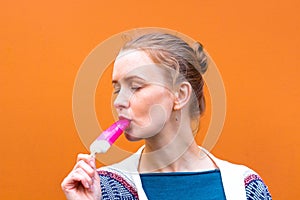 Beautiful and young girl eats a pink hue ice cream and enjoys. She closed her eyes from enjoying eating ice cream.