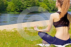 Beautiful young girl is engaged in sports, yoga, fitness on the beach by the river on a Sunny summer day