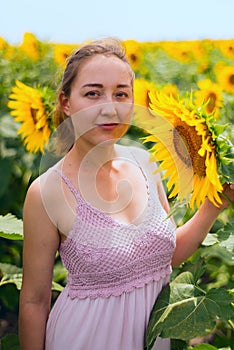 Beautiful young girl enjoying nature on the field of sunflowers at sunset