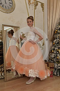 Beautiful young girl with evening haircut in pink with white a  lash by a gilded mirror, fitting