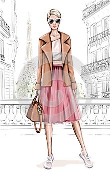 Beautiful young girl in fashion clothes. Stylish woman with Paris background. Fashion girl holding bag. Fashion look.