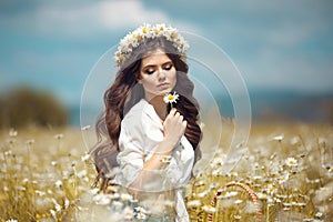 Beautiful young girl with flower enjoying in chamomile field. Carefree happy brunette woman with chaplet on healthy wavy hair