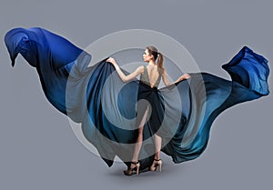 Beautiful young girl in flying dress. Flowing fabric. Light transparent fabric flutters in the wind