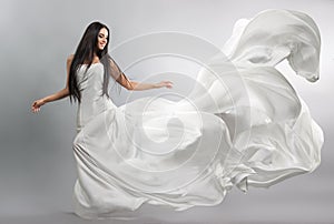 Beautiful young girl in flying white dress. Flowing fabric. Light white cloth flying