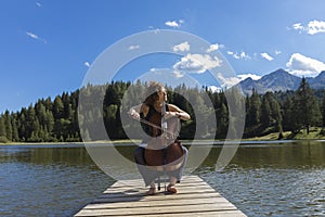 Beautiful young girl and former woman plays her cello on a wooden jetty