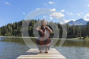 Beautiful young girl and former woman plays her cello on a wooden jetty