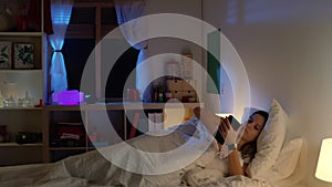 Beautiful young girl getting in the bed at night in her room. slow motion RED camera cinematographic video.