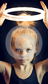 Beautiful young girl gymnast holding aloft a glowing circle