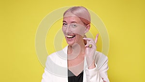 Beautiful young girl happily agreeing on camera over yellow background