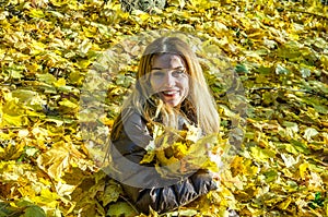 The beautiful young girl a happy woman smiling and holding a yellow maple leaves walking in autumn park