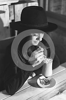 Beautiful young girl in hat drinking coffee in cafe