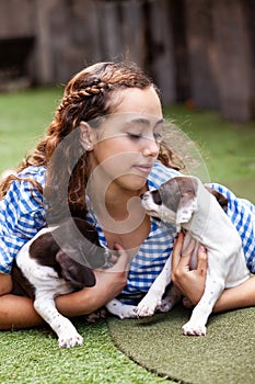 Beautiful young girl having fun with her small French Braque puppies