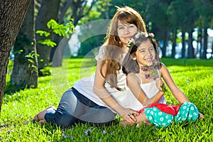 Beautiful young girl with her mother on lush grass