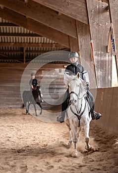 beautiful young girl on her white pony during her riding lesson