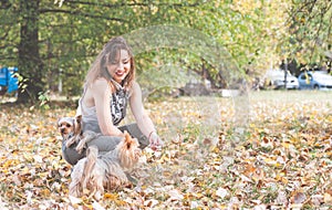 Beautiful young girl with her Yorkshire terrier dog puppy enjoying and playing in the autumn day in the park selective focus