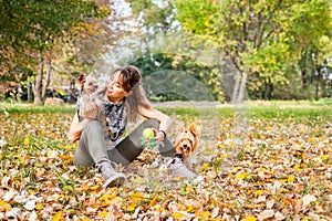 Beautiful young girl with her Yorkshire terrier dog puppy enjoying and playing in the autumn day in the park selective focus