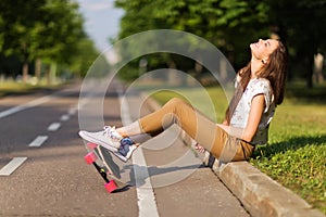 Beautiful young girl hipster sneakers t-shirt and pants put on sneakers and longboard happy. Skateboarding. lifestyle