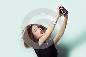 Beautiful young girl hipster takes photos, shoots selfe, taking pictures of himself on camera in jeans and a black t-shirt