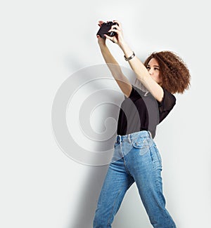 Beautiful young girl hipster takes photos, shoots selfe, taking pictures of himself on camera in jeans and a black t-shirt