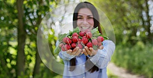 Beautiful young girl holding a clean radish in the hand, in the background of nature. Concept: biology, bio products, bio ecology,