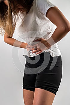 beautiful young girl holds her stomach, which has spasms.