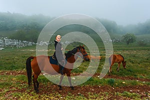 Beautiful young girl on a horse in the mountains in the mist