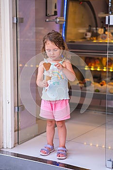 Beautiful young girl with ice cream in hand. Young woman holding ice cream and smiling. Bright sunny day in resort city