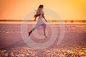 Beautiful young girl jumping on the salt lake at sunset
