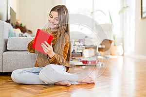 Beautiful young girl kid using digital touchpad tablet sitting on the floor with a happy face standing and smiling with a