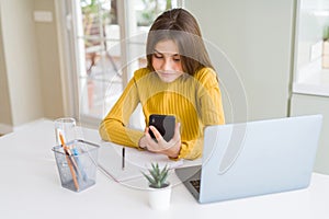 Beautiful young girl kid using smartphone and computer laptop with a confident expression on smart face thinking serious