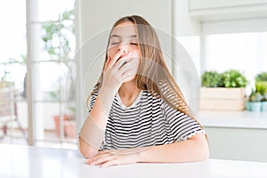 Beautiful young girl kid wearing stripes t-shirt bored yawning tired covering mouth with hand