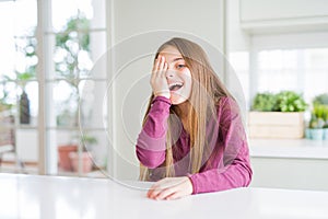 Beautiful young girl kid on white table covering one eye with hand with confident smile on face and surprise emotion