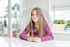 Beautiful young girl kid on white table skeptic and nervous, frowning upset because of problem